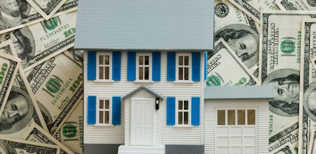 White and blue home for sale on top of a pile of cash